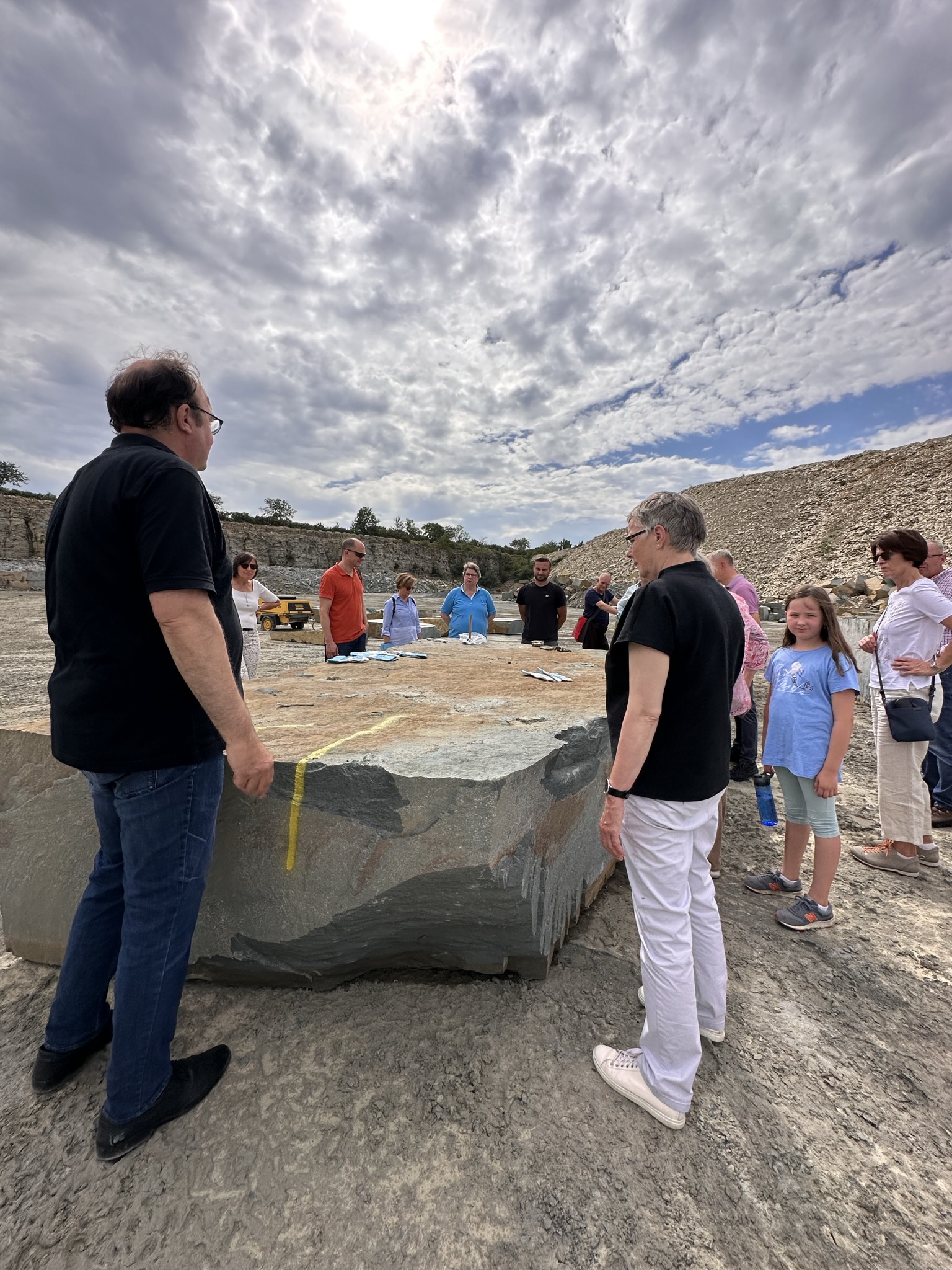 Gruppe im Steinbruch um großen Stein versammelt